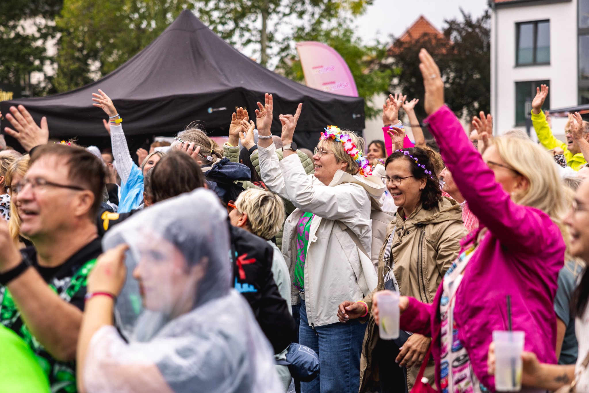Publikum mit Blumenkränzen und erhobenen Händen
