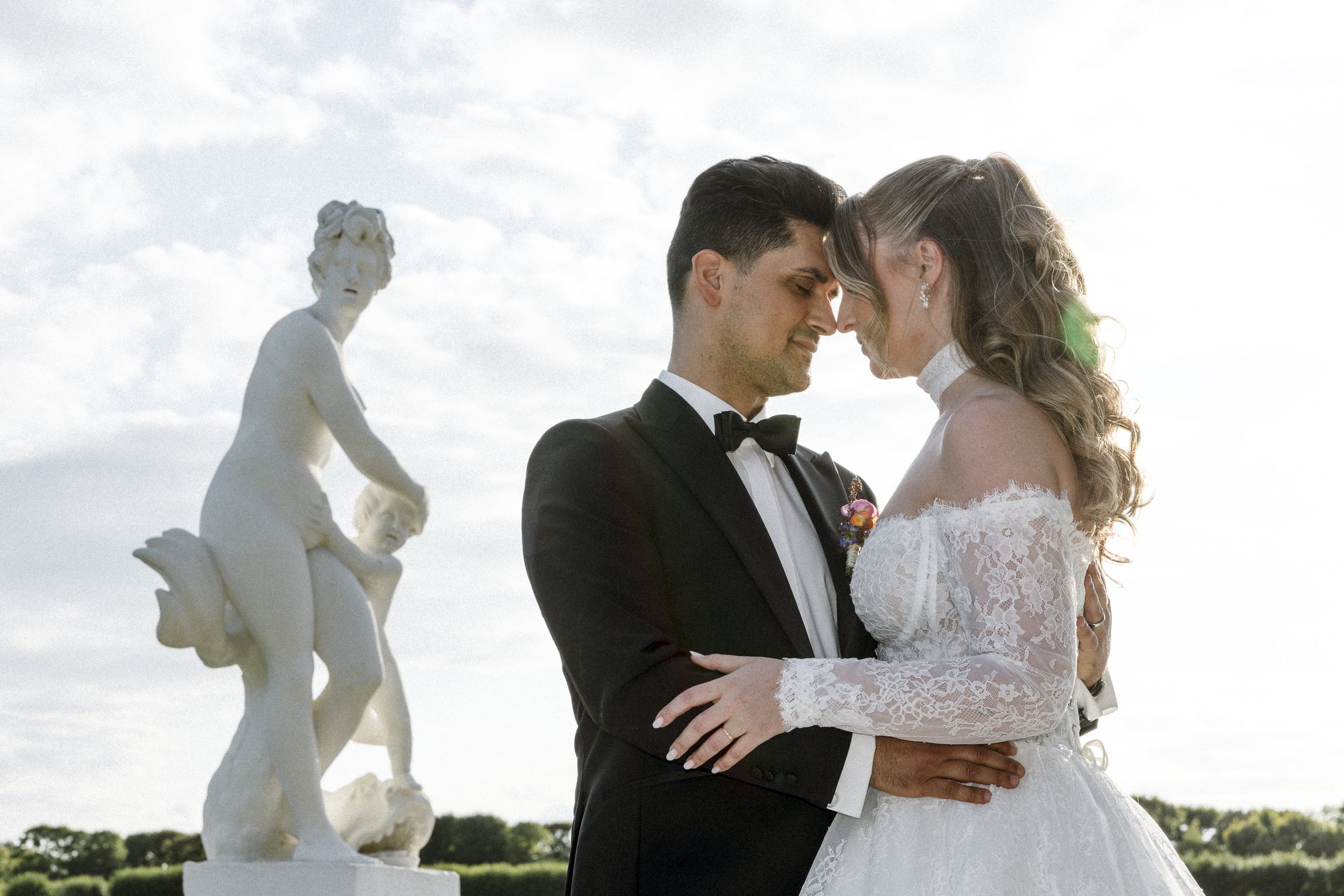 Brautpaar Stirn an Stirn neben einer Statue