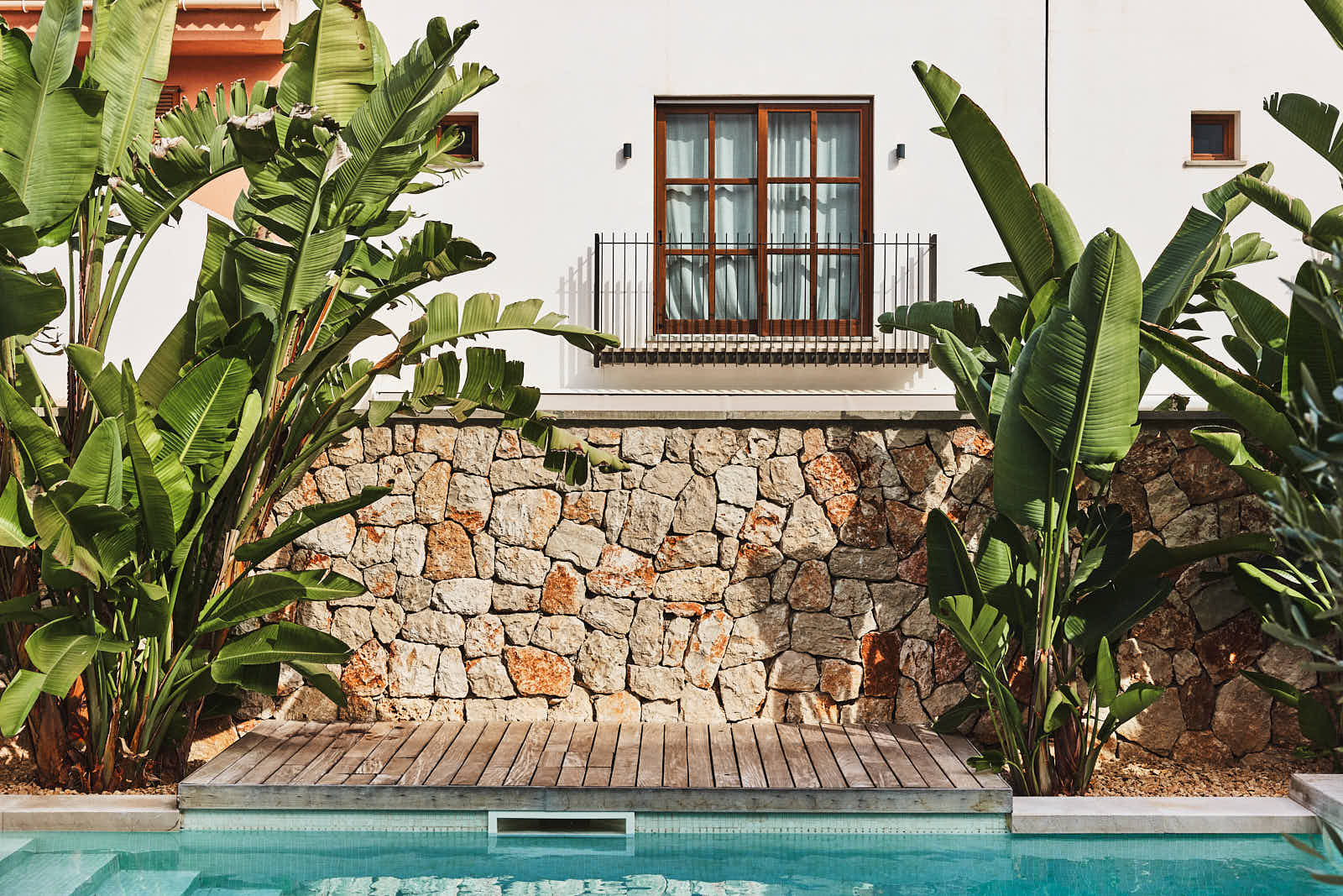 Pool vor Natursteinmauer und Fassade