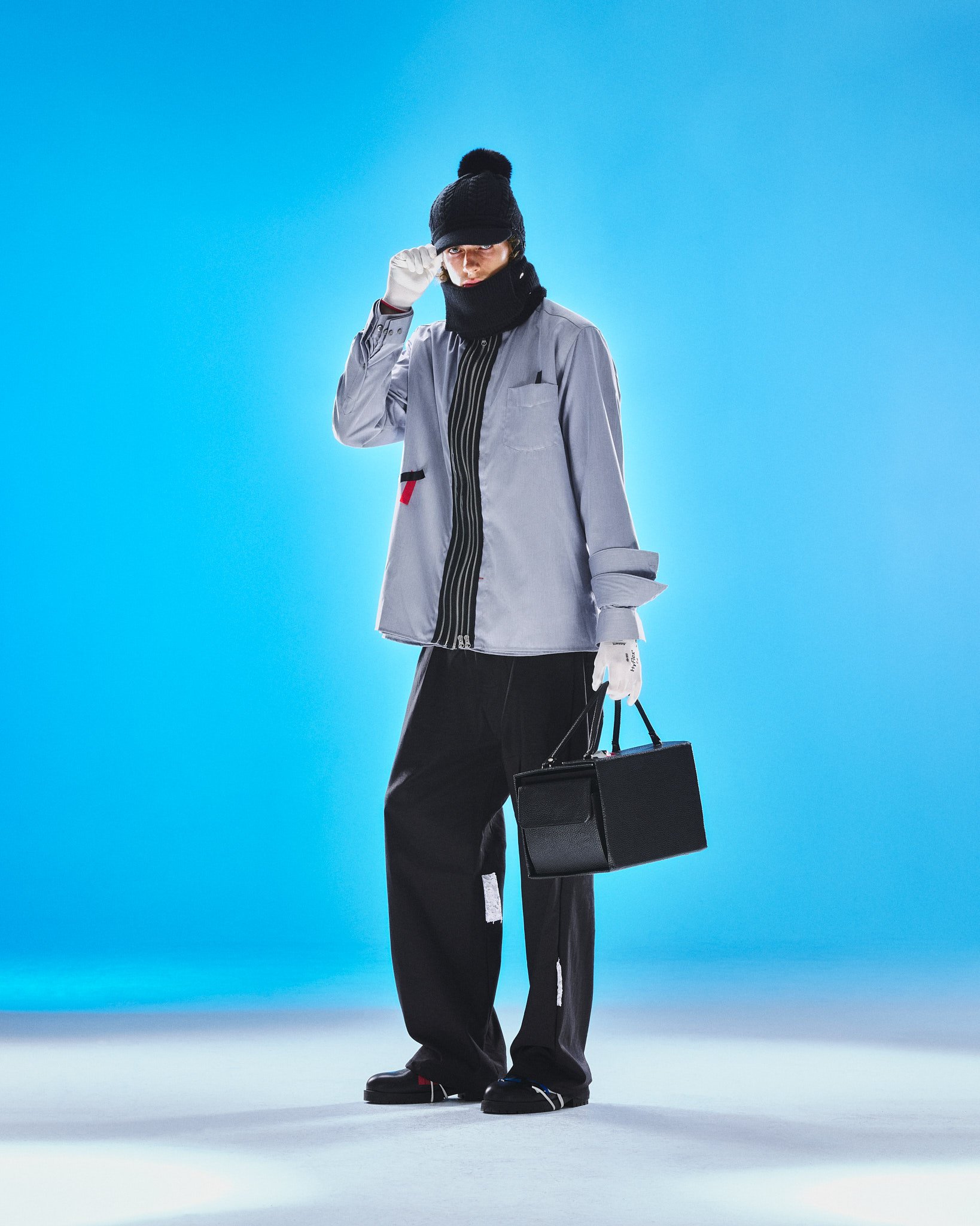 Graue Oversize-Jacke mit schwarzer Handtasche, blauer Hintergrund